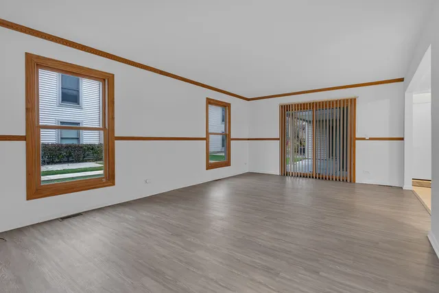 a view of a big room with wooden floor and windows