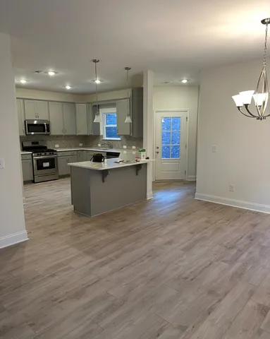 a kitchen with stainless steel appliances granite countertop a sink a stove and a wooden floors