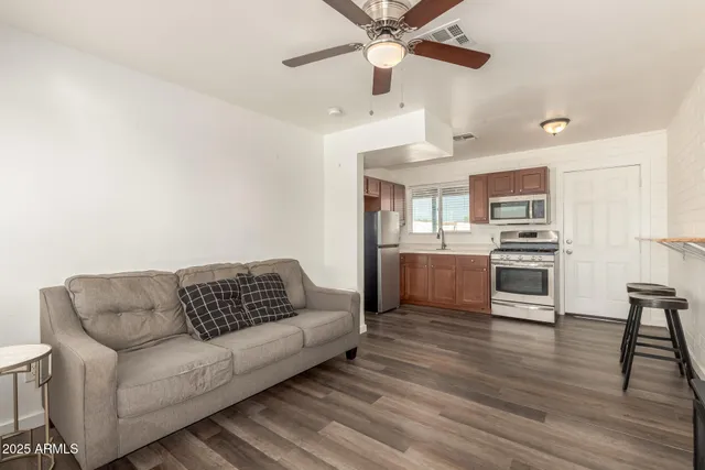 a living room with stainless steel appliances furniture and a kitchen view