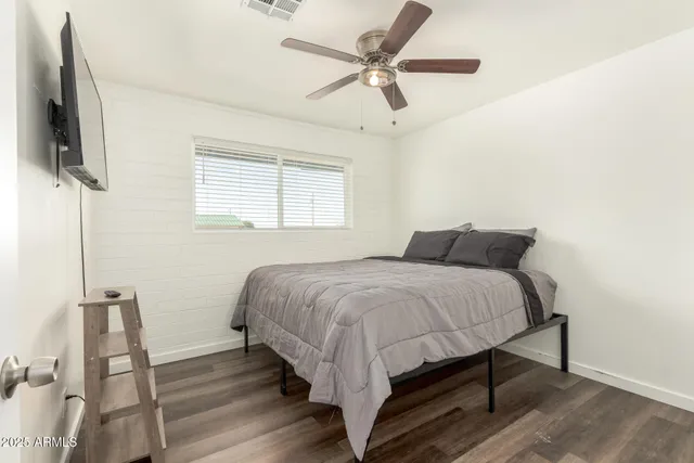 a bedroom with a bed a flat screen tv and a ceiling fan