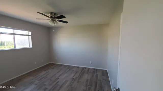 an empty room with wooden floor fan and windows