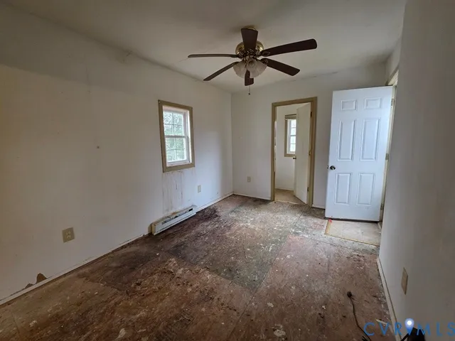 an empty room with a ceiling fan and windows