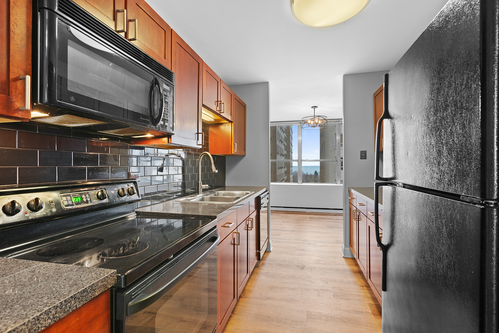 655 West Irving Park Road, Unit 701 Chicago, IL 60613 - Photo 24 of 39 a kitchen with stainless steel appliances granite countertop a refrigerator a stove and a sink with wooden floor