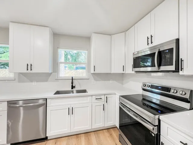 a kitchen with white cabinets appliances and a sink