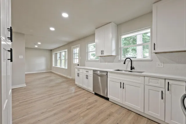 a kitchen with white cabinets and wooden floors