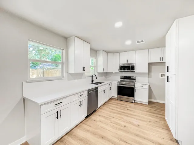 a kitchen with granite countertop white cabinets and white stainless steel appliances