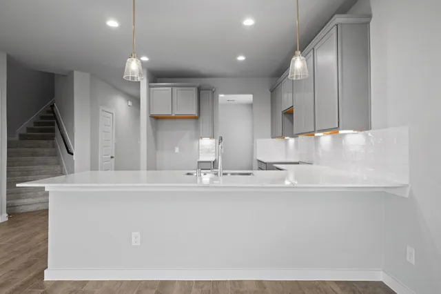 a large white kitchen with wooden floors and stainless steel appliances