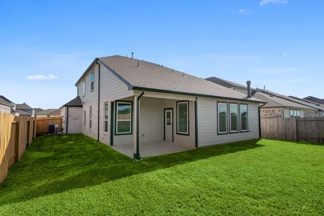 a view of a house with a yard plants and large tree