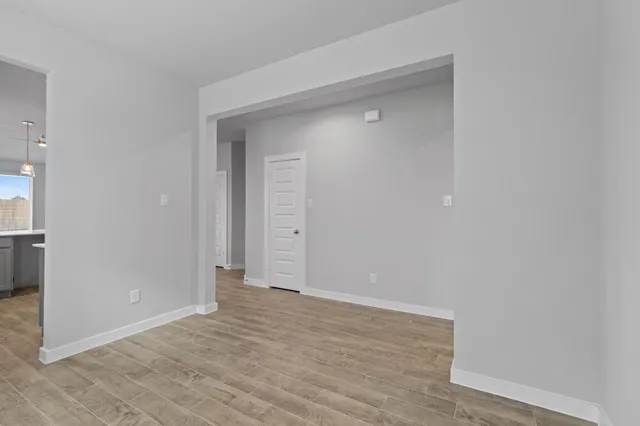 a view of an empty room with wooden floor and closet