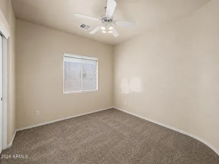 an empty room with a chandelier fan and closet area