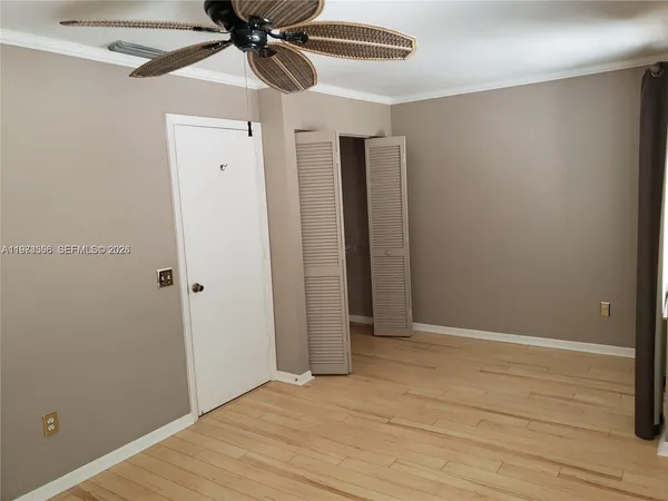 an empty room with wooden floor fan and windows