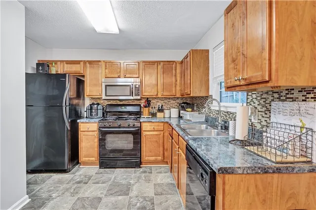 a kitchen with stainless steel appliances granite countertop a stove a refrigerator and a sink