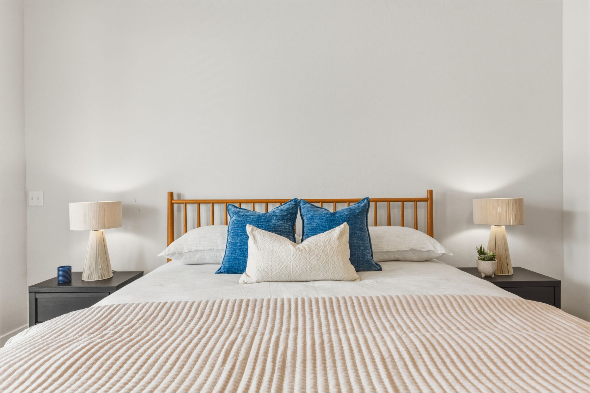 2929 Moreno Street Austin, TX 78723 - Photo 31 of 40 Light-filled bedroom featuring a wood-spindle headboard, neutral wall color, and matching bedside tables