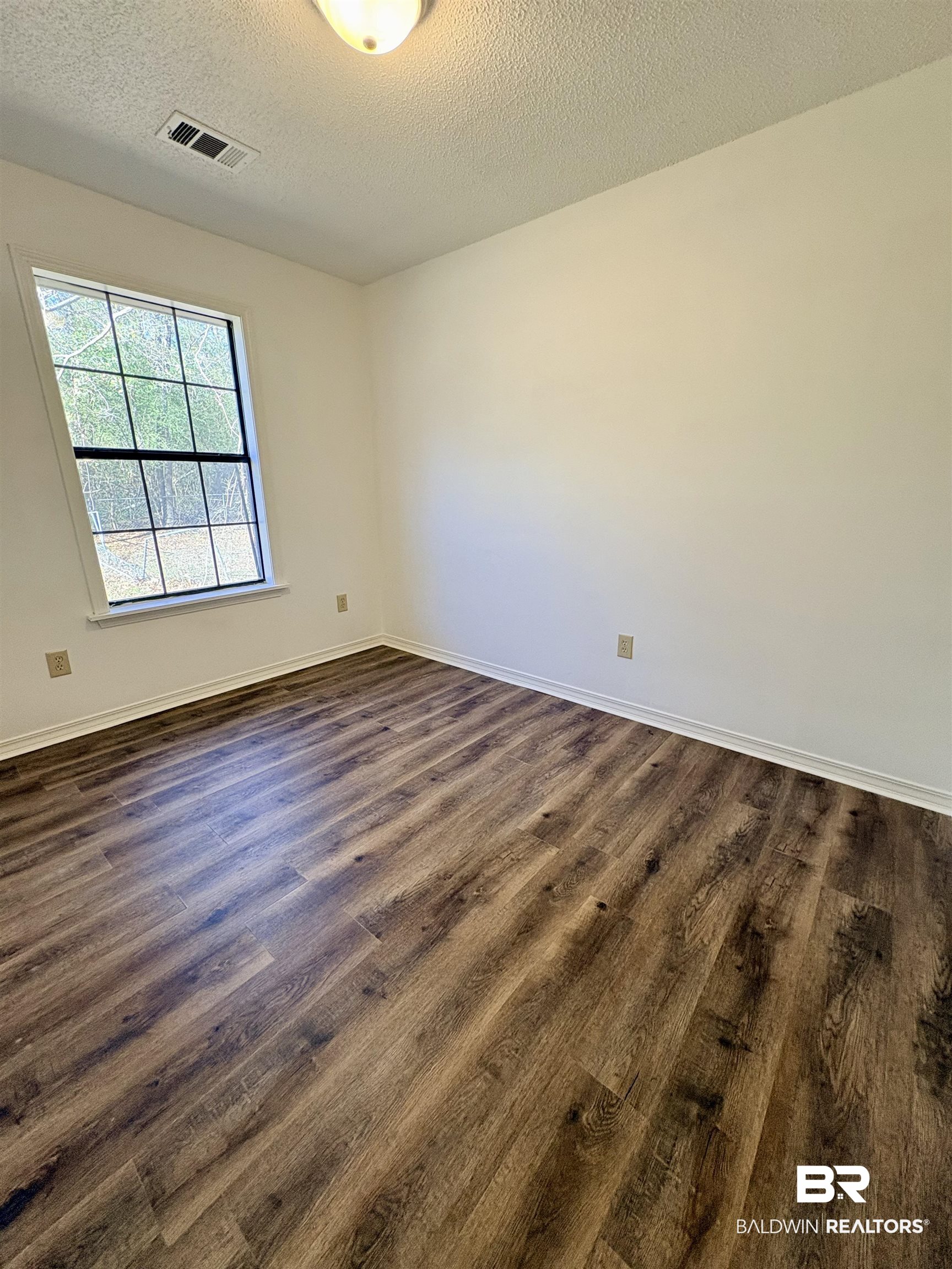 47 Fairview Street Evergreen, AL 36401 - Photo 5 of 15 Empty room with a textured ceiling and dark wood-type flooring