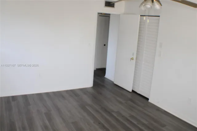 a view of an empty room with wooden floor and a ceiling fan