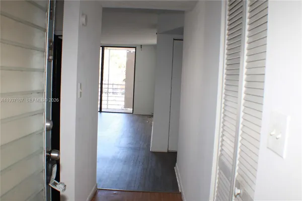 a view of a hallway with wooden floor and a bathroom