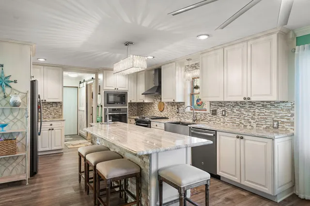 a large kitchen with stainless steel appliances kitchen island granite countertop a lot of counter space and wooden floors
