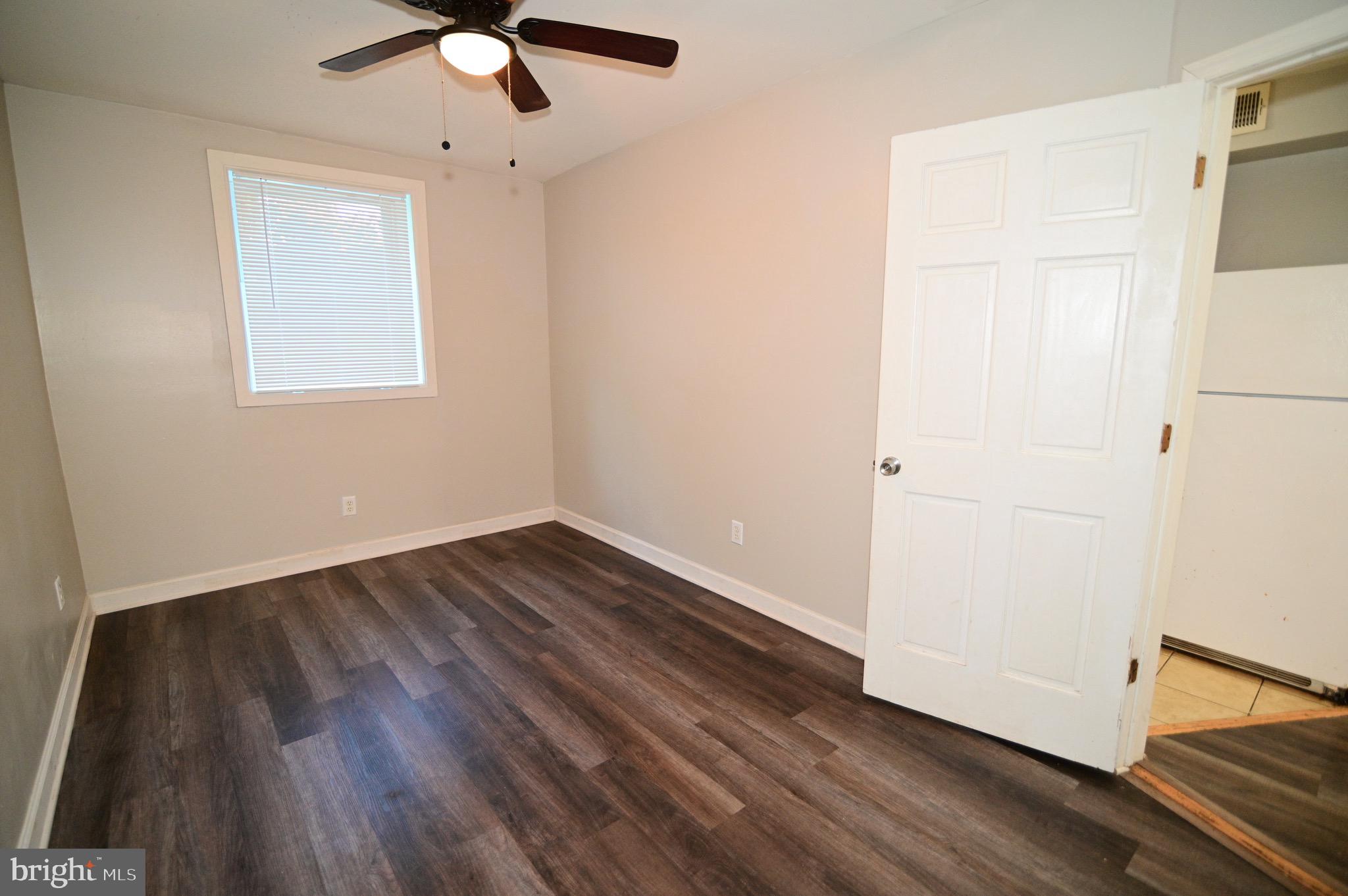 431 Mellon Street Southeast, Unit 2 Washington, DC 20032 - Photo 17 of 24 an empty room with wooden floor chandelier fan and windows