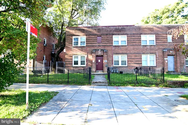 a view of a brick house with a yard and plants
