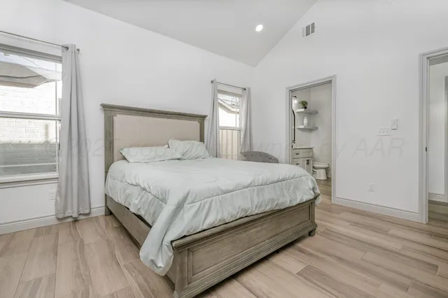 a large bed sitting in a spacious bedroom next to a window and a chandelier