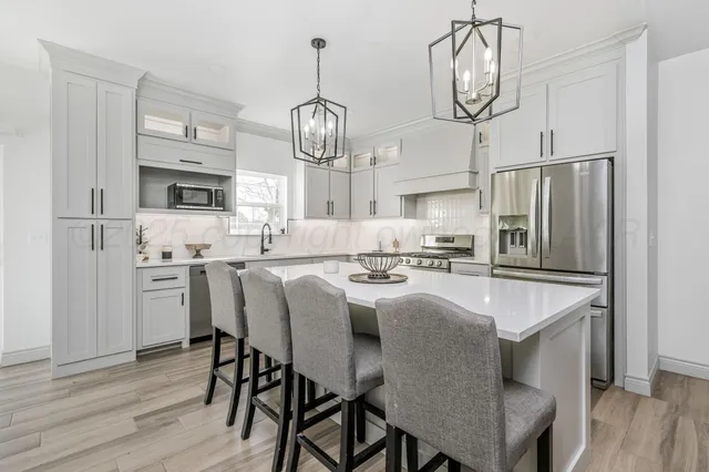 a kitchen with stainless steel appliances granite countertop a sink a stove a refrigerator cabinets and wooden floor