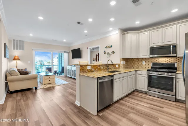 a large kitchen with stainless steel appliances granite countertop a stove and a wooden floors