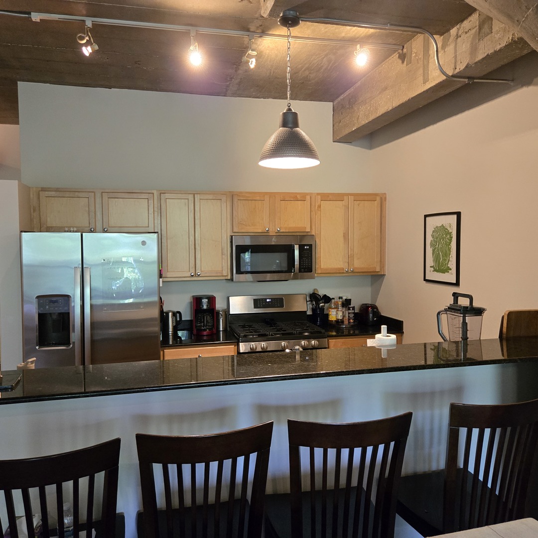 1111 West 15th Street, Unit 228 Chicago, IL 60608 - Photo 14 of 32 a kitchen with stainless steel appliances a center island wooden floor and a counter top space