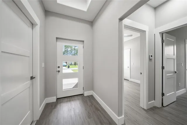 a view of a hallway to an empty room and wooden floor