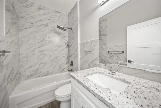 a bathroom with a granite countertop sink a toilet and bathtub