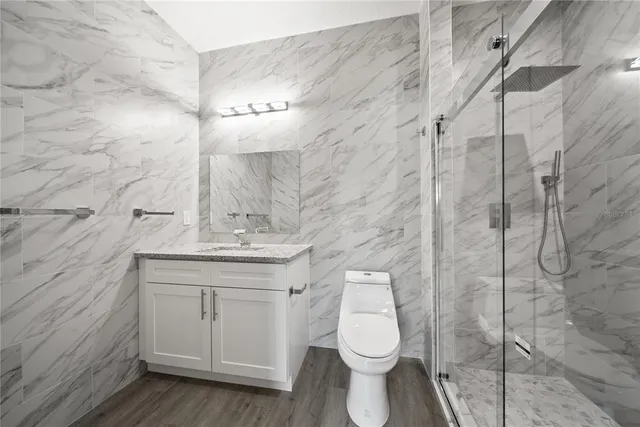 a bathroom with a granite countertop toilet a sink and a shower