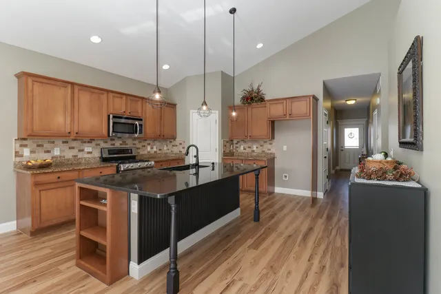 a large kitchen with stainless steel appliances kitchen island granite countertop a stove a sink dishwasher and a refrigerator