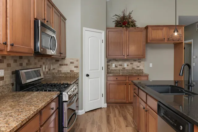 a kitchen with granite countertop a sink stainless steel appliances and cabinets
