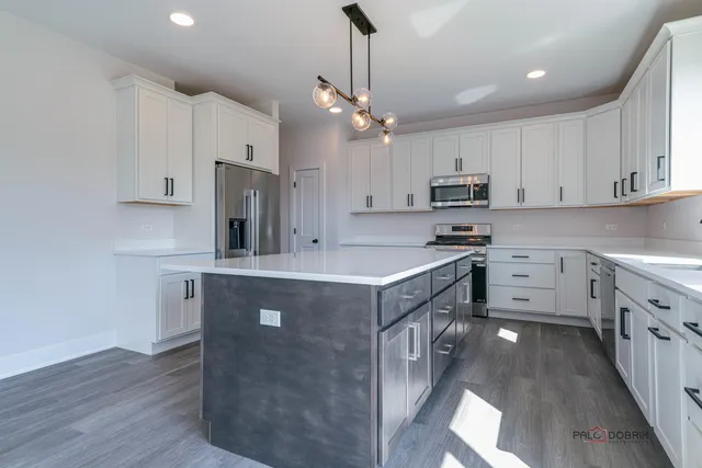 a kitchen with kitchen island granite countertop a sink a counter top space stainless steel appliances and cabinets