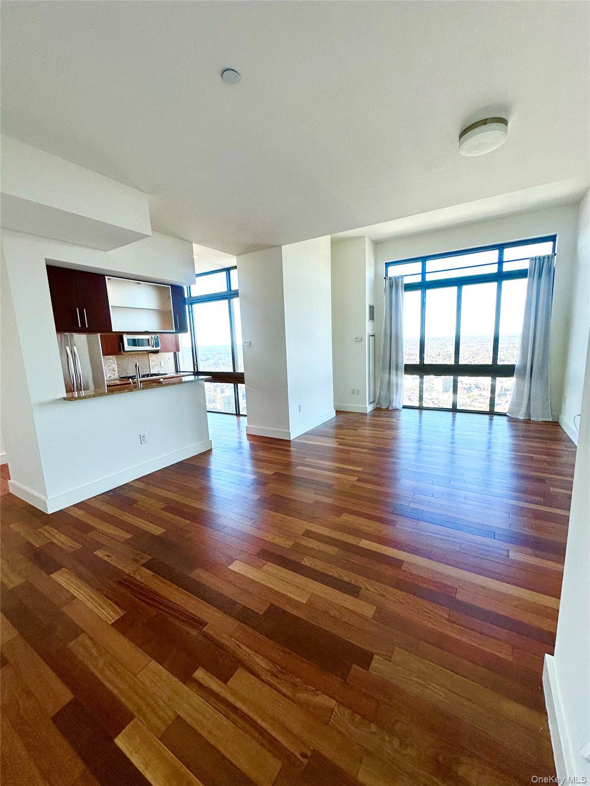 Unfurnished living room with dark wood-style flooring and baseboards
