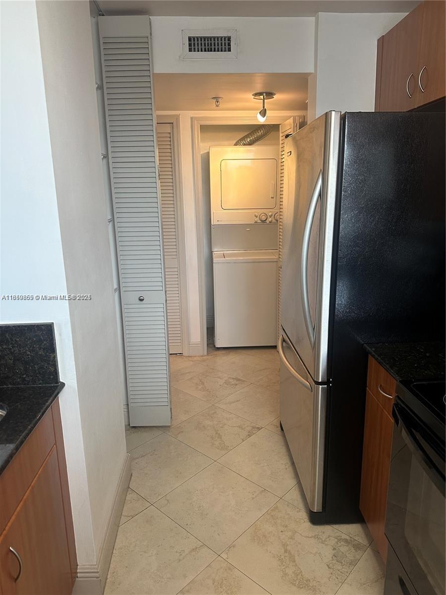 2400 Southwest 27th Avenue, Unit 406 Miami, FL 33145 - Photo 6 of 31 a view of a refrigerator in kitchen and an empty room in wooden floor