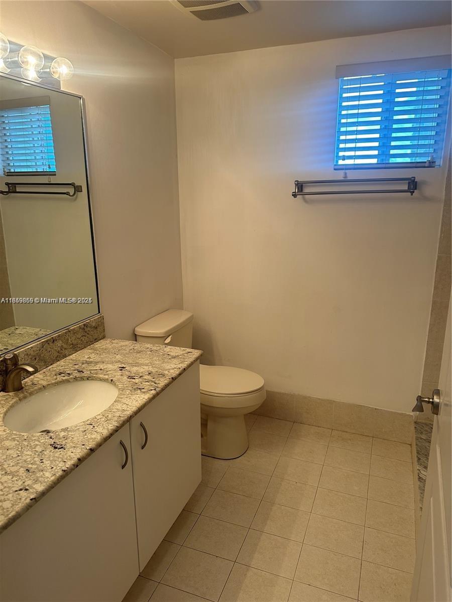 2400 Southwest 27th Avenue, Unit 406 Miami, FL 33145 - Photo 9 of 31 a bathroom with a granite countertop sink a toilet and a mirror
