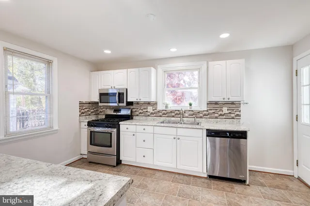 a kitchen with granite countertop a stove sink and microwave