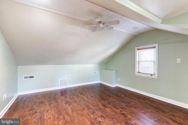 a view of an empty room with wooden floor and a ceiling fan
