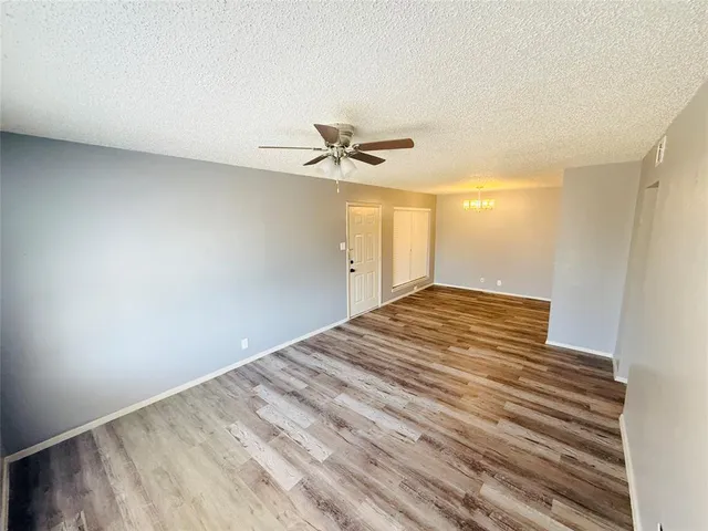an empty room with a ceiling fan and wooden floor