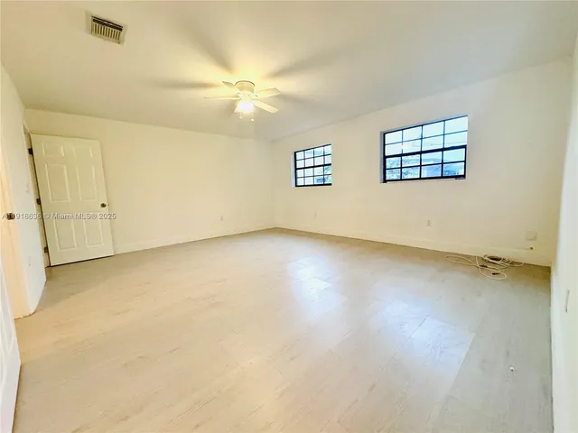 an empty room with windows and ceiling fan