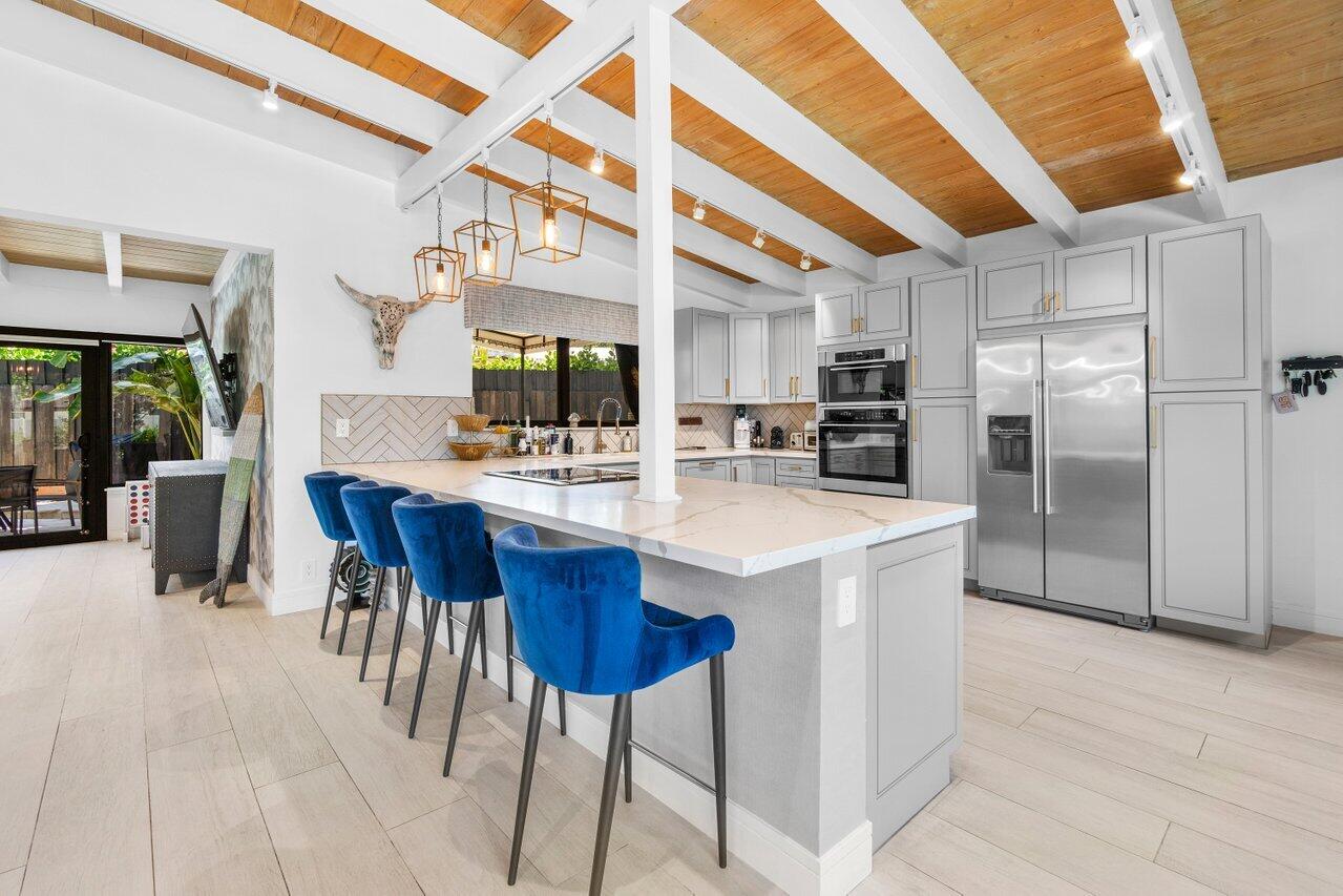 308 Enfield Road Delray Beach, FL 33444 - Photo 7 of 25 a kitchen with stainless steel appliances kitchen island granite countertop a table chairs and a refrigerator