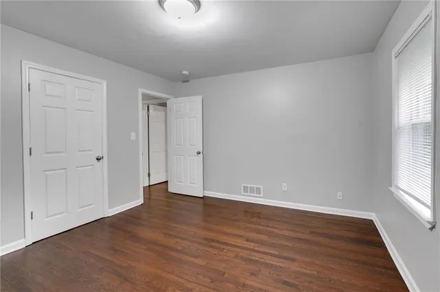 a view of an empty room with wooden floor and window