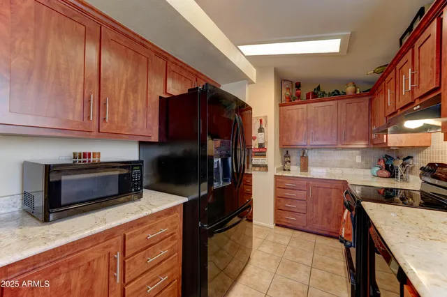 a kitchen with stainless steel appliances kitchen island granite countertop a stove refrigerator and cabinets
