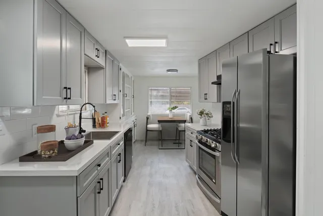 a kitchen with stainless steel appliances a refrigerator sink and white cabinets