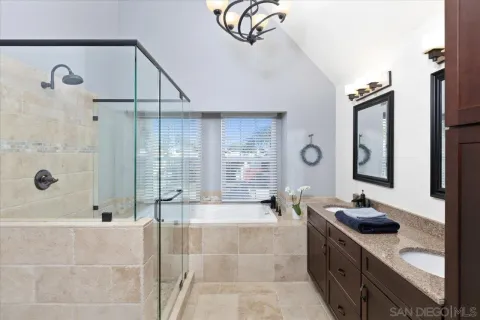 a bathroom with a granite countertop sink a mirror a bathtub and shower