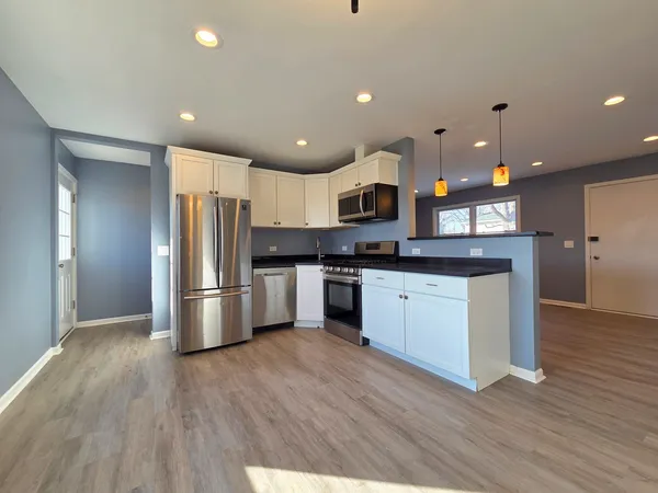 a kitchen with kitchen island a white counter top space a refrigerator and cabinets