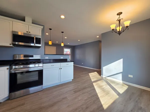 a kitchen with stainless steel appliances granite countertop a stove and a wooden floors