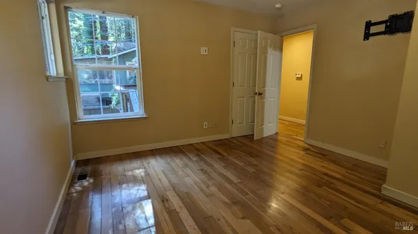 a view of an empty room with wooden floor and a window