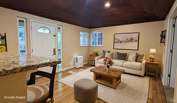 a living room with furniture a wooden floor and kitchen view
