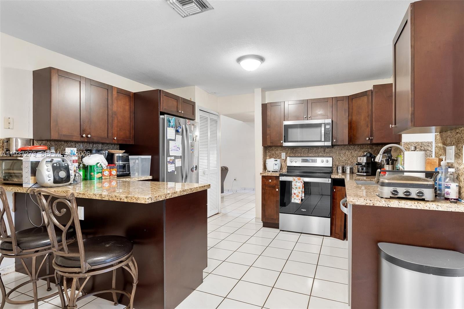 14256 Southwest 92nd Street Miami, FL 33176 - Photo 13 of 56 a kitchen with stainless steel appliances granite countertop a stove top oven a sink dishwasher a dining table and chairs
